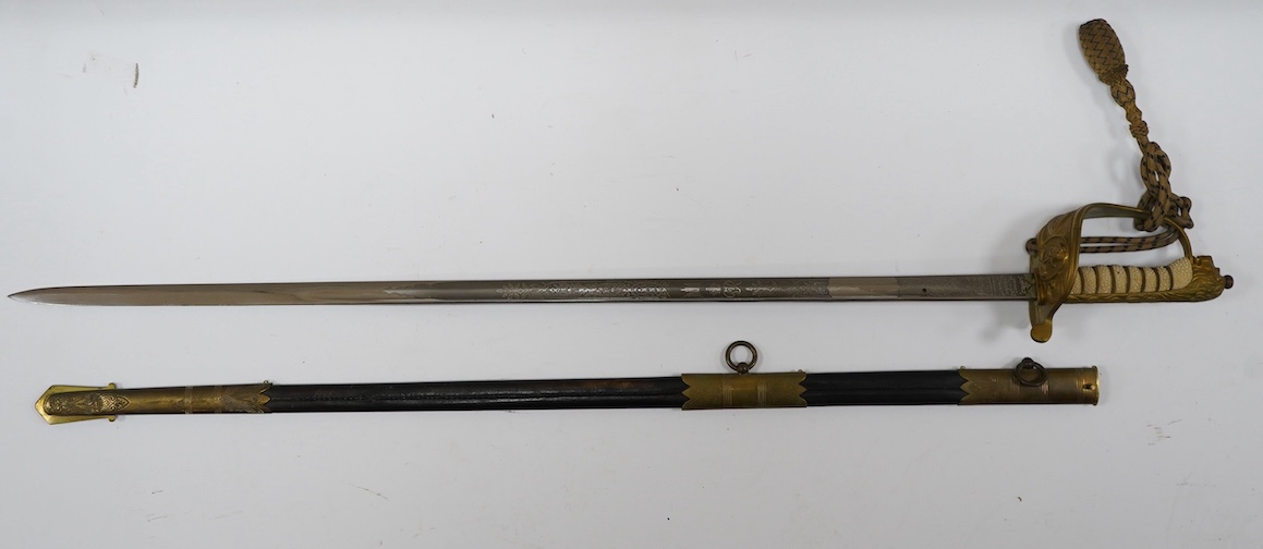 A George VI naval officer’s dress sword by Wilkinson (unnumbered), with regulation brass hilt with folding guard, engraved P.A.R. Gould R.N., bullion dress knot, in its brass mounted leather scabbard and contained in its